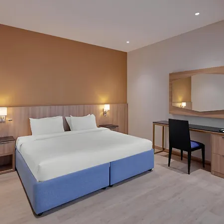 Makarem Umm Al Qura Hotel Mecca Exterior photo The photo shows a modern hotel room featuring a large bed with white linens and plush pillows. The walls are painted in warm tones, enhancing the cozy atmosphere. There are bedside lamps for lighting, and a simple wooden desk with a chair is position