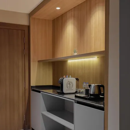 Makarem Umm Al Qura Hotel Mecca Exterior photo The photo shows a small kitchenette area with wooden cabinetry. The upper cabinets feature a light wood finish, while there is a black countertop below. On the countertop, there is a coffee machine, a kettle, and a few glassware items. Soft lighting 
